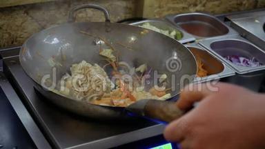 厨师在平底锅中往乌顿面和炒菜中倒入大豆和烤酱